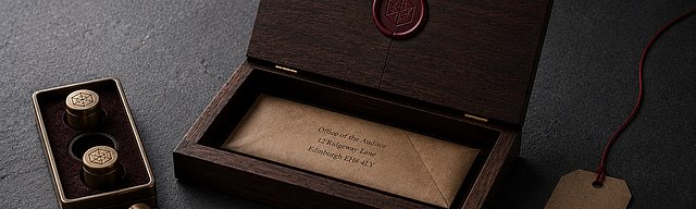 Ein hölzerner Briefkasten-Deckel auf glattem Beton mit feinem Riss im präzisen Wachssiegel; im Inneren ein unbeschädigter Briefumschlag, daneben ein Messing-Stempel-Set mit einem leicht verrutschten Stempel und eine Kraftpapier-Etikette mit oxblutfarbenem Faden im kühlen Nordlicht.