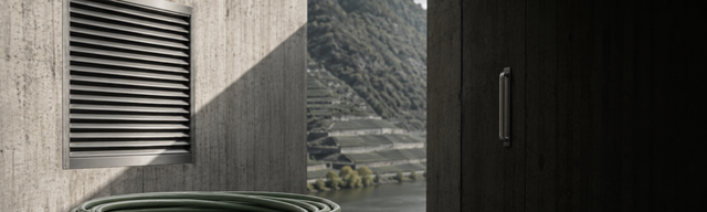 Halb geöffnete Betontür eines modernen Rechenzentrums — davor ein dunkles Slate-Plinth mit einem aufgerollten oxblood-Kabel und einem Rack-Modul mit Kraft-Paper-Etikett, im Hintergrund die Mosel-Weinberghänge.