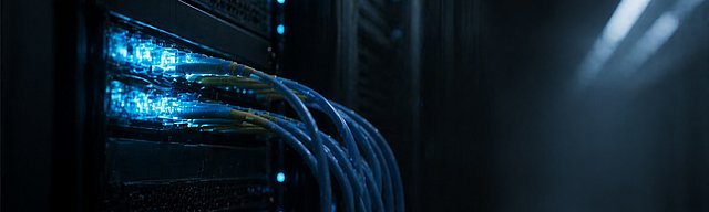 Serverschrank im halbdunklen Rechenzentrum mit leuchtenden blauen Status-LEDs an einem Patchfeld.