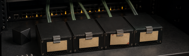 Dunkles 19-Zoll-Rack mit FrankenPHP-Worker-Hosts: matt-schwarze Edge-Boxen, sage-grüne Patch-Kabel an den Switch-Ports, ein Modul-Cartridge mit Kraftpaper-Mono-Label und einem einzelnen oxblood-Etikett. Status-LEDs der Switch-Frontblende leuchten ruhig pulsierend, die rechte Bildhälfte fällt in tiefes Schwarz ab und lässt Negative Space für das Title-Overlay.